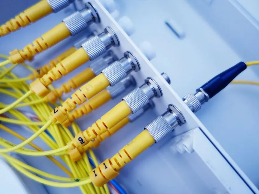 Close-up of yellow fiber optic cables in a network server, showcasing fast data transfer.